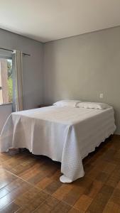 a white bed in a bedroom with a wooden floor at Chalés ninhos do cerrado in Cavalcante