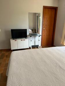 a bedroom with a bed and a flat screen tv at Chalés ninhos do cerrado in Cavalcante