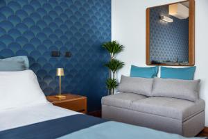 a bedroom with a bed and a couch and a mirror at Le Rose Suites - Misano World Circuit & Beach in Misano Adriatico