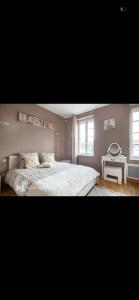 a bedroom with a large white bed and a table at Chez mimi et Ludo in Saint-Étienne-au-Mont