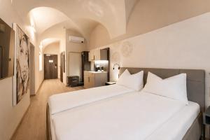 une chambre avec un grand lit blanc et une cuisine dans l'établissement Aparthotel Lavilo City Center, à Graz