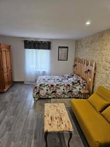a bedroom with a bed and a couch and a table at La petite ferme 37 in Épeigné-les-Bois