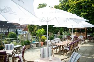 a patio with tables and chairs with white umbrellas at Hotel Kronprinz in Bad Salzdetfurth