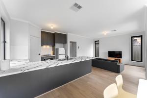 eine offene Küche und ein Wohnzimmer mit einer Theke in der Unterkunft Stylish Luxury 4BR - Close to Wineries & City in Munno para Downs