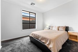 ein Schlafzimmer mit einem großen Bett und einem Fenster in der Unterkunft Stylish Luxury 4BR - Close to Wineries & City in Munno para Downs