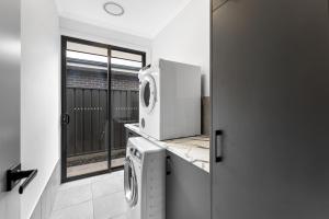eine Küche mit Waschmaschine und Trockner auf der Arbeitsfläche in der Unterkunft Stylish Luxury 4BR - Close to Wineries & City in Munno para Downs + 3 Fotos