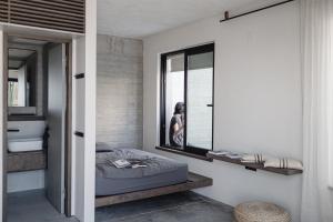 a woman standing in a bedroom with a bed and a mirror at Ukino House in Nikiana