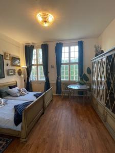 a bedroom with a bed and a table and windows at Baroque Palais Timber House Celle in Celle