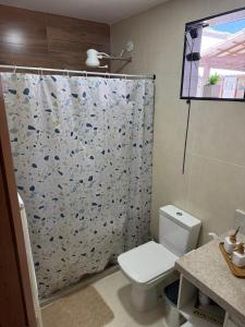 a bathroom with a toilet and a shower curtain at Suite LUAR in Saquarema