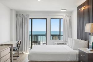 a bedroom with a bed and a balcony with the ocean at Grande Beach Resort in Myrtle Beach