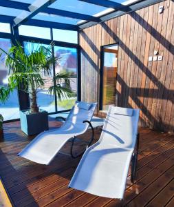 two white chairs on a deck with a palm tree at Žolynų namai in Klaipėda