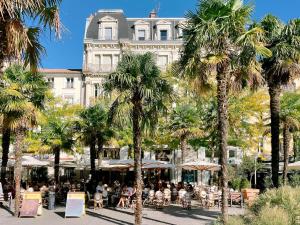 a group of people sitting at tables in front of a building at L'Appart du Faubourg 1 à 8 Personnes in Valence