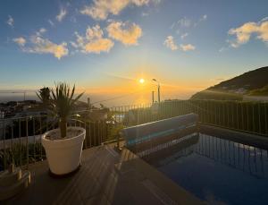 a potted plant sitting on a balcony with the sunset at Blue Villa in Arco da Calheta