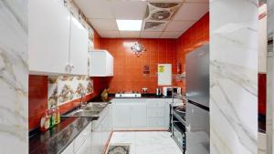 a kitchen with white cabinets and an orange wall at Happiness Farm in Hatta