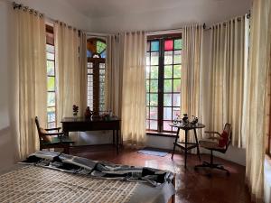 a bedroom with a bed and a desk and windows at Fort flora in Cochin