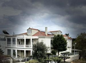 a large white house with a balcony on a cloudy day at Casa Kelly Chios in Chios