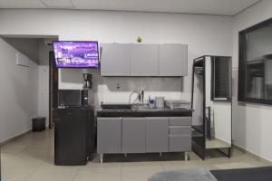 a kitchen with a sink and a refrigerator and a tv at Studio IV Jundiaí - Com Ar Condicionado in Jundiaí