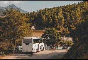 a white bus driving down a road next to a building at Antoni Guest House & Café in Lekaj +7 photos