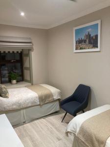a bedroom with two beds and a blue chair at Oakdale Lodge in Derrymore Bridge