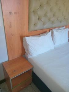 a bed with a wooden headboard next to a night stand at Star Legend lodge in Parow