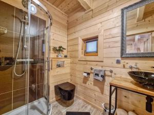 a wooden bathroom with a shower and a sink at Kunatówka domek w Zębie in Ząb