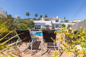 two chairs sitting on a patio with an orange tree at Authentic apartment with pool and sea view in Estepona