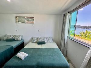 a bedroom with two beds and a large window at Casa de praia em Itacuruçá in Mangaratiba