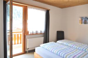 a bedroom with a bed and a sliding glass door at Chasa Arlu in Samnaun
