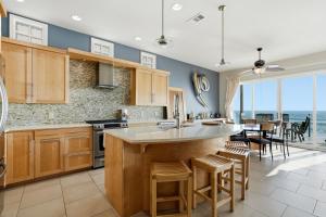 a kitchen with wooden cabinets and a large island with bar stools at Oceanfront 3BR Condo, Balcony, Fire Pit, Shared Beach, Sleeps 6 in Oceanside