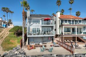 a large house on the beach with palm trees at Oceanfront 3BR Condo, Balcony, Fire Pit, Shared Beach, Sleeps 6 in Oceanside