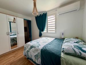 a bedroom with a bed with a blue comforter and windows at Kaz a Ma-Lu in Le Marin +9 photos