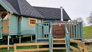 a green house with a deck and a house at Oak Hill Escape in Welshpool