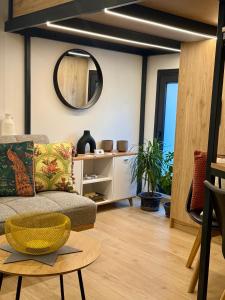 a living room with a couch and a round mirror at La Petite Mansion, next to the city center! in Volos +19 photos
