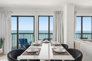 a dining room with a table and chairs with a view of the ocean at Grande Beach Resort in Myrtle Beach