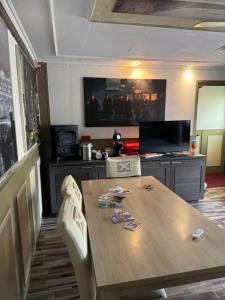 a dining room table with chairs and a television at Slotje in Egmond aan den Hoef