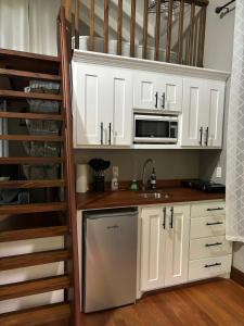 a kitchen with white cabinets and a sink and a microwave at Enchanted Jungle Treehouse in Spanish Lookout +38 photos
