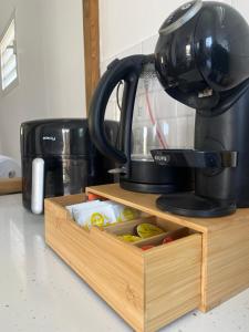 a black coffee maker sitting on top of a wooden drawer at La maison de Vénus - Petite maison créole à 3 min du front de mer - proche de la plage de la Pointe Faula - kitesurf et activités nautiques in Le Vauclin