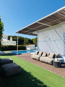 a patio with a couch under a pavilion next to a pool at Villa Amêndoa in Loulé