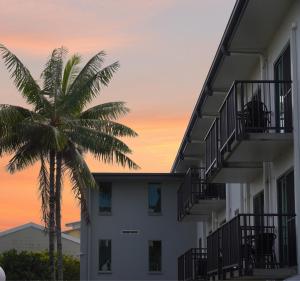 a building with a palm tree in front of a sunset at Heritage Cairns Hotel in Cairns