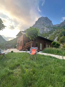 two chairs in the grass in front of a house at Bujtina Alpine Vanat in Bele