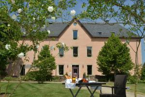 ein großes rosa Haus mit einem Tisch davor in der Unterkunft HÔTEL LA FERME DE BOURRAN - RODEZ - parking privé avec bornes pour voitures électriques in Rodez