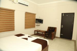 a bedroom with a bed and a chair and a desk at Kalathil Kshetra Inn in Guruvāyūr