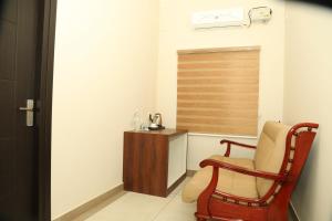 a room with a chair and a wooden cabinet at Kalathil Kshetra Inn in Guruvāyūr