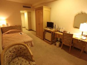 a hotel room with a bedroom with a bed and a desk at Nogami President Hotel in Iizuka