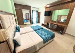 a bedroom with a bed and a desk and a mirror at Hôtel La Pivoine in Abidjan +22 photos