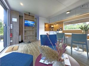 a living room with a blue couch and a kitchen at Feriendorf Seeblick - Tiny Chalet Nr 9 in Neunburg vorm Wald