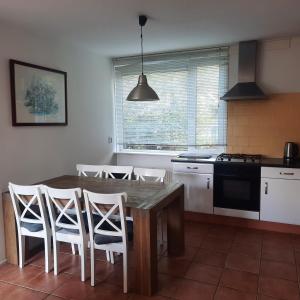 a kitchen with a wooden table and white chairs at Slufterduin 80 in De Cocksdorp