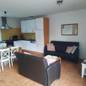 a living room with a black couch and a kitchen at Slufterduin 80 in De Cocksdorp +4 photos