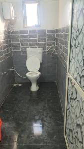 a bathroom with a toilet in a tiled room at Umahomestay in Nashik