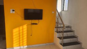 a flat screen tv on a yellow wall next to stairs at Umahomestay in Nashik +7 photos